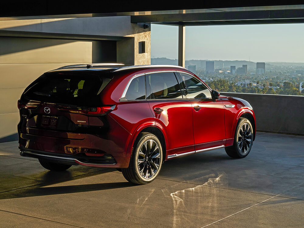 Un CX-90 rouge artisan dans un stationnement au coucher du soleil.   